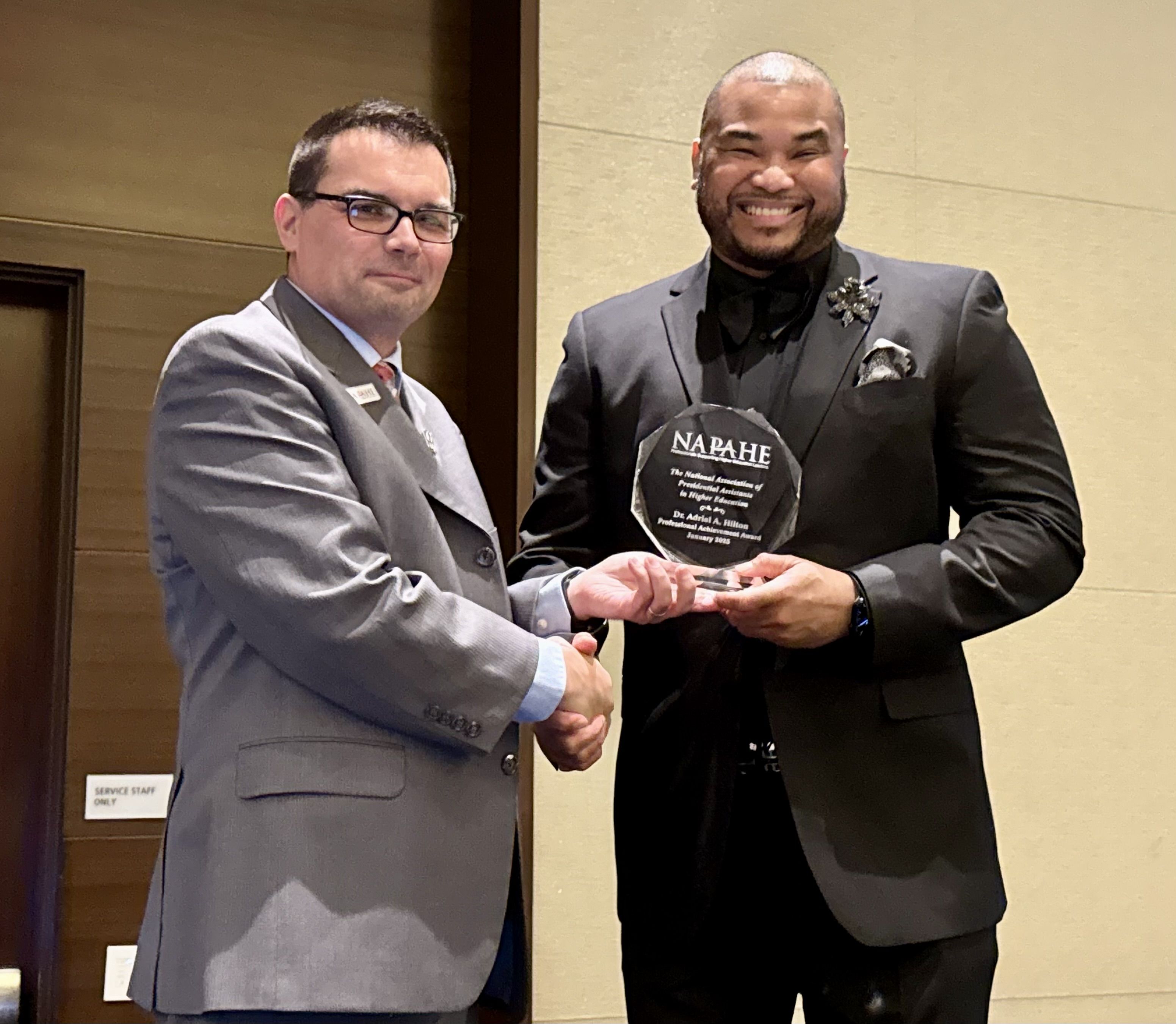 Dr. Adriel A. Hilton (right) poses for a picture with NAPAHE's Board Chair, Michael Sass (left), after receiving the 2025 Award for Professional Achievement.